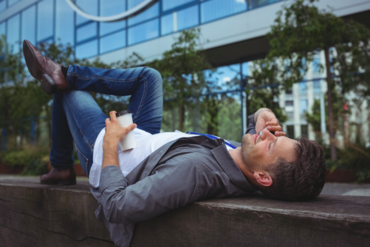 Handsome business executive lying on wood while talking on mobile phone